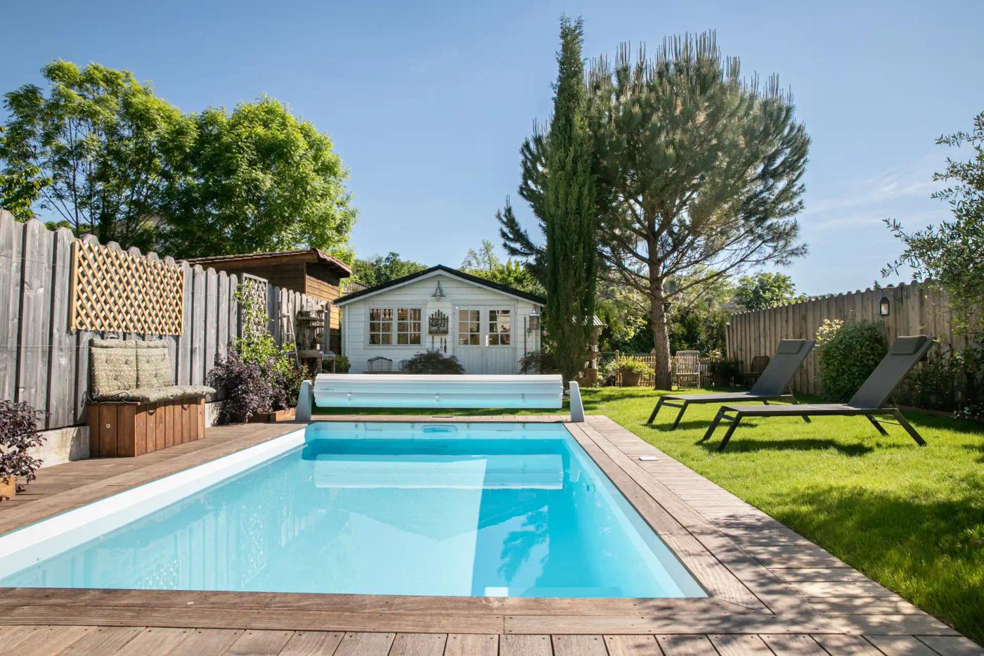 Bassin Fidji 6 devant un abri de jardin, avec terrasse en bois et couverture hors-sol.