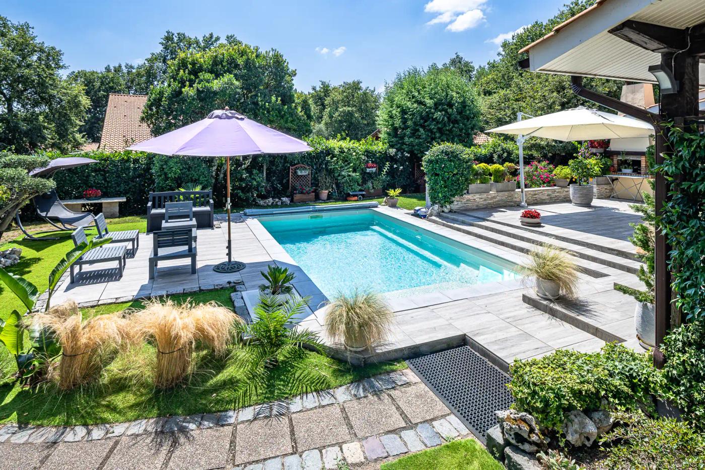 Bassin Maeva 6 installé entre une terrasse aménagée et un jardin.